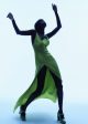 Sudanese model Adot Gak poses with her arms up while wearing a silky lime green dress and John Fluevog Shoes green Mille Miglia platform mary-janes.