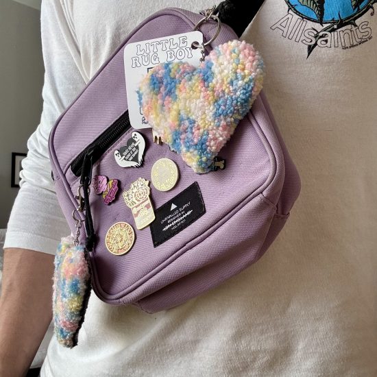 Hand-tufted rug accessories attached to a bag.